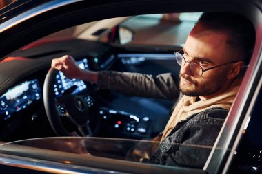 Arabasına binen şık giyinmiş, tıraşsız yakışıklı adamın yan görüntüsü..