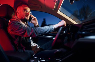 Telefonla konuşuyorum. Kırmızı ışık. Şık giyinmiş, traşsız yakışıklı bir adam otomobiline biniyor..