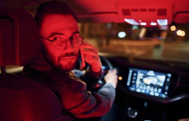 Telefonla konuşuyorum. Kırmızı ışık. Şık giyinmiş, traşsız yakışıklı bir adam otomobiline biniyor..