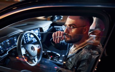 Sigara içiyorum. Şık giyinmiş, traşsız yakışıklı bir adam otomobiline biniyor..