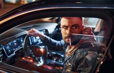 Sigara içiyorum. Şık giyinmiş, traşsız yakışıklı bir adam otomobiline biniyor..