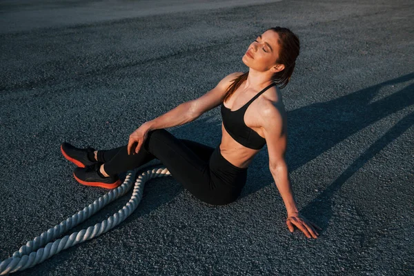 Spor kıyafetli bir kadın akşam vakti yolda düğümlerle oturuyor..