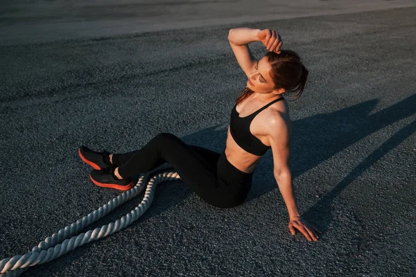 Spor kıyafetli bir kadın akşam vakti yolda düğümlerle oturuyor..
