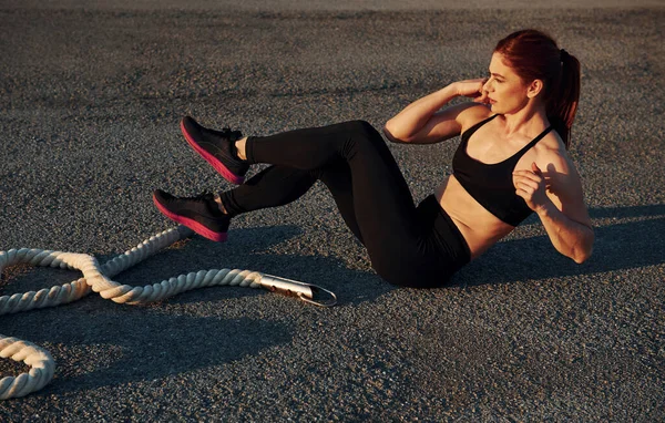 Spor kıyafetli bir kadın akşam vakti yolda karın kası yapıyor..