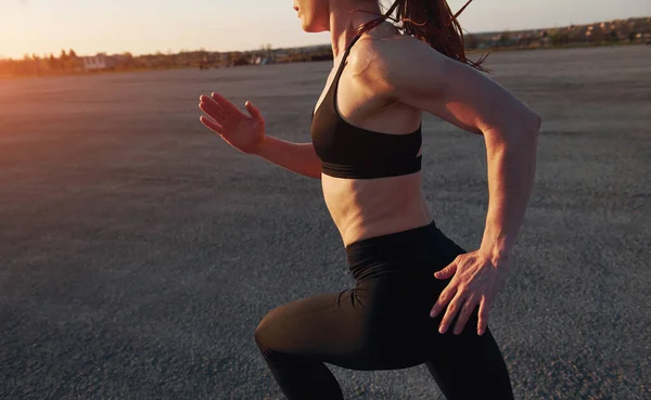 Spor kıyafetli bir kadın akşam vakti yolda koşuyor..