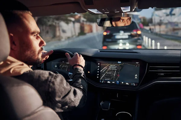 Arabasına binen şık giyinmiş, tıraşsız, yakışıklı adamın arka manzarası..