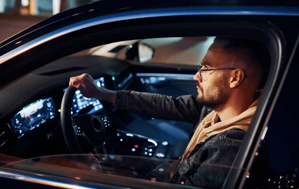 Arabasına binen şık giyinmiş, tıraşsız yakışıklı adamın yan görüntüsü..