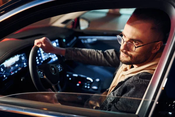 Arabasına binen şık giyinmiş, tıraşsız yakışıklı adamın yan görüntüsü..