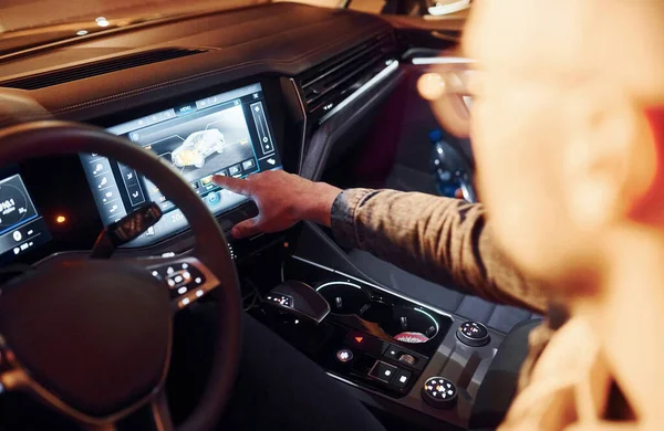 Navigasyon ekranı kullanılıyor. Şık giyinmiş, traşsız yakışıklı bir adam otomobiline biniyor..