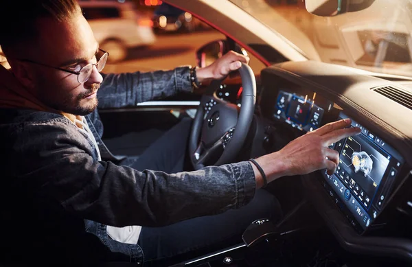Navigasyon ekranı kullanılıyor. Şık giyinmiş, traşsız yakışıklı bir adam otomobiline biniyor..