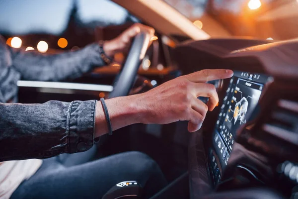 Navigasyon ekranı kullanılıyor. Şık giyinmiş, traşsız yakışıklı bir adam otomobiline biniyor..