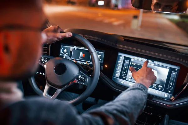 Navigasyon ekranı kullanılıyor. Şık giyinmiş, traşsız yakışıklı bir adam otomobiline biniyor..