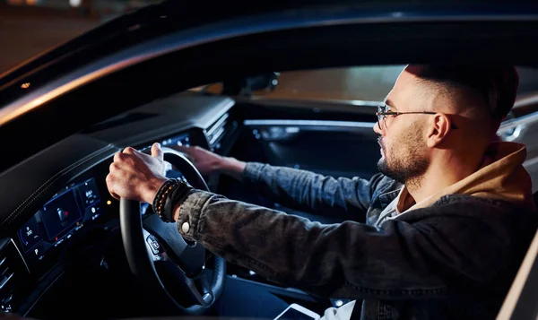 Arabasına binen şık giyinmiş, tıraşsız yakışıklı adamın yan görüntüsü..