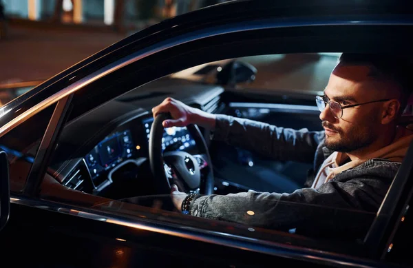 Arabasına binen şık giyinmiş, tıraşsız yakışıklı adamın yan görüntüsü..