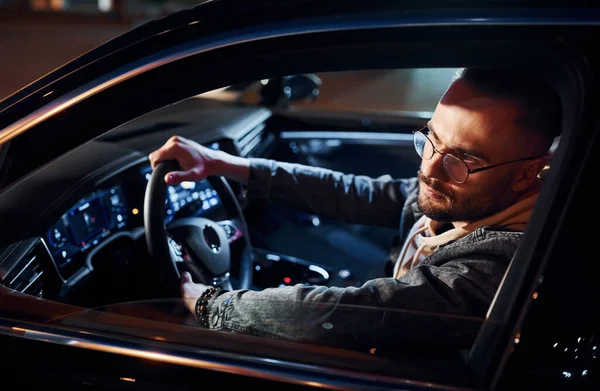 Arabasına binen şık giyinmiş, tıraşsız yakışıklı adamın yan görüntüsü..