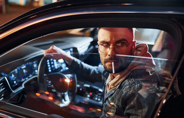 Sigara içiyorum. Şık giyinmiş, traşsız yakışıklı bir adam otomobiline biniyor..