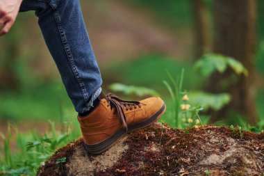 Close up view of man's legs on the rock in forest. Traveler have a walk.