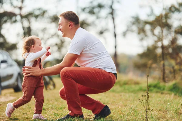 Günlük giysiler içinde bir baba ormanda kızıyla yürüyüşe çıkar ve eğlenir..