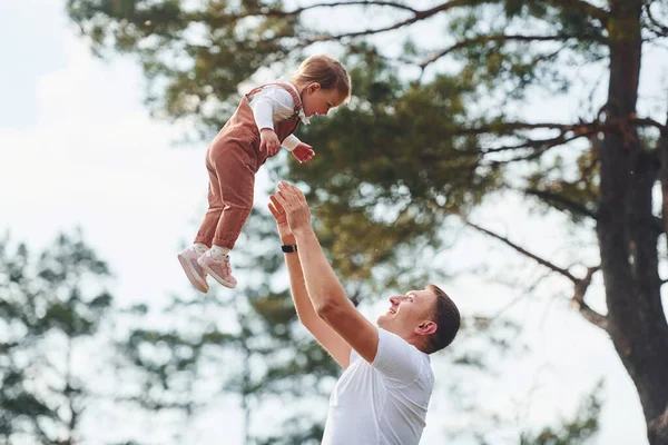Günlük giysiler içinde bir baba ormanda kızıyla yürüyüşe çıkar ve eğlenir..
