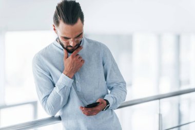 Telefonla. Gündüz vakti ofiste resmi kıyafetler içinde genç yakışıklı bir adam..