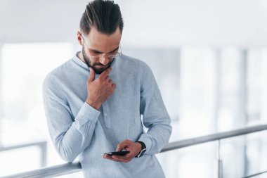 Telefonla. Gündüz vakti ofiste resmi kıyafetler içinde genç yakışıklı bir adam..