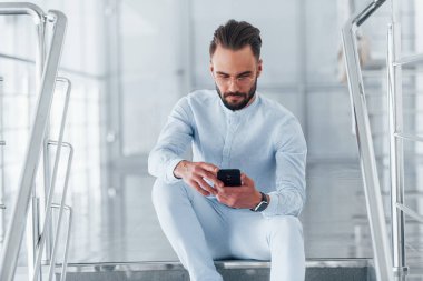 Merdivenlerde otururken. Gündüz vakti ofiste resmi kıyafetler içinde genç yakışıklı bir adam..