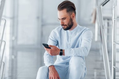 Merdivenlerde otururken. Gündüz vakti ofiste resmi kıyafetler içinde genç yakışıklı bir adam..