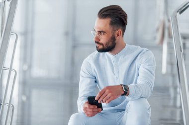 Merdivenlerde otururken. Gündüz vakti ofiste resmi kıyafetler içinde genç yakışıklı bir adam..