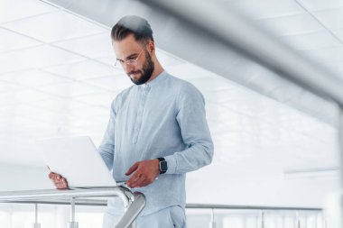 Laptop kullanıyorum. Gündüz vakti ofiste resmi kıyafetler içinde genç yakışıklı bir adam..