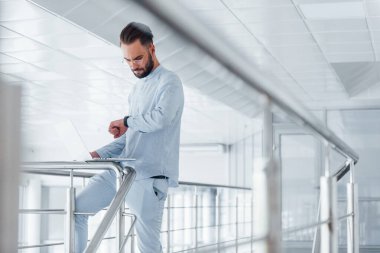 Laptop kullanıyorum. Gündüz vakti ofiste resmi kıyafetler içinde genç yakışıklı bir adam..