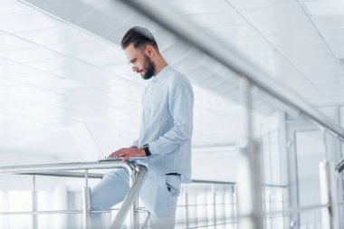 Laptop kullanıyorum. Gündüz vakti ofiste resmi kıyafetler içinde genç yakışıklı bir adam..