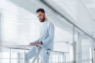 Laptop kullanıyorum. Gündüz vakti ofiste resmi kıyafetler içinde genç yakışıklı bir adam..