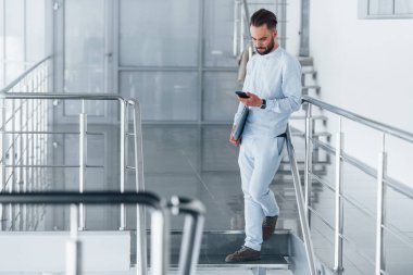 Telefonla. Gündüz vakti ofiste resmi kıyafetler içinde genç yakışıklı bir adam..