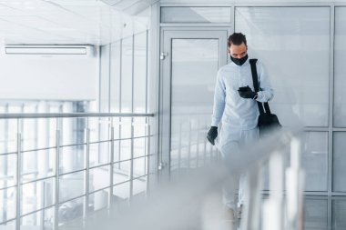 Koruyucu maske ve eldivenlerle. Gündüz vakti ofiste resmi kıyafetler içinde genç yakışıklı bir adam..