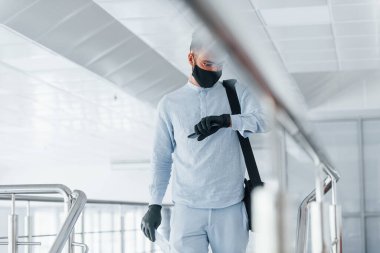Koruyucu maske ve eldivenlerle. Gündüz vakti ofiste resmi kıyafetler içinde genç yakışıklı bir adam..