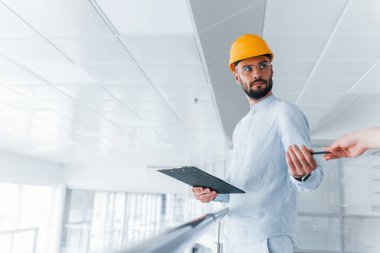 Kızdan kaleme. Not defterini tutuyorum. Beyaz elbiseli ve turuncu koruyucu şapkalı mühendis içeride duruyor ve çalışıyor..