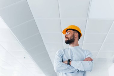 Beyaz elbiseli mühendis portresi ve kapalı alanda çalışan turuncu koruyucu şapka..