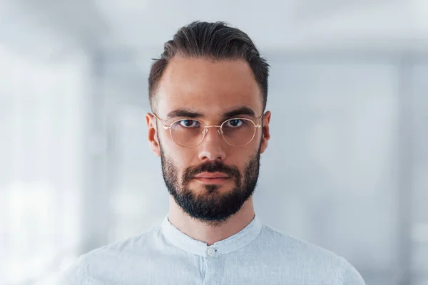 Portrait of young handsome man in formal clothes indoors in the office at daytime.