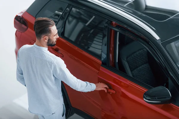 Kırmızı otomobilin yanında duran beyaz giysili zarif genç adam..