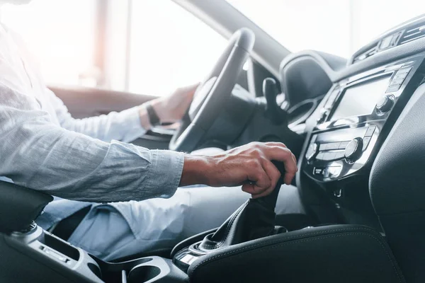 Gıcır gıcır yeni bir otomobilde oturan resmi kıyafetli genç adamın yan görüntüsü..