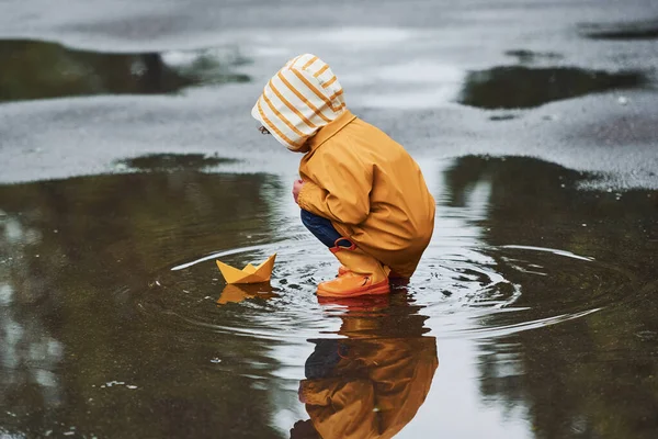 Kind Geel Waterdichte Mantel Laarzen Spelen Met Papieren Handgemaakte Boot — Stockfoto