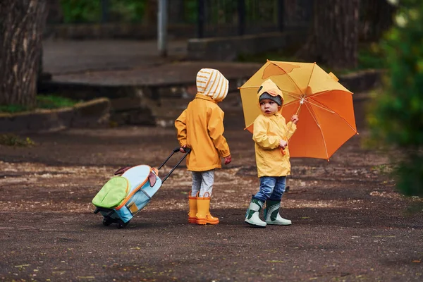 Two Kids Umbrella Suitcase Yellow Waterproof Cloaks Boots Walking Outdoors — Stok fotoğraf