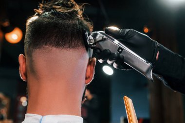 Berber dükkanında oturan ve saçını kestiren genç sakallı adama yakından bakın..