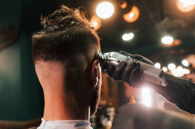 Berber dükkanında oturan ve saçını kestiren genç sakallı adama yakından bakın..