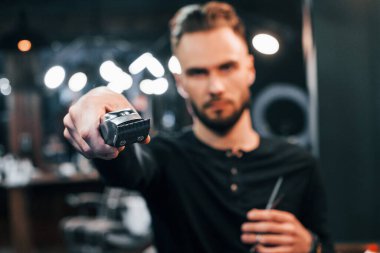 Berber dükkanında elinde makasla duran sakallı genç adam..