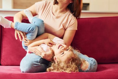 Young mother with her little daughter in casual clothes together indoors at home.