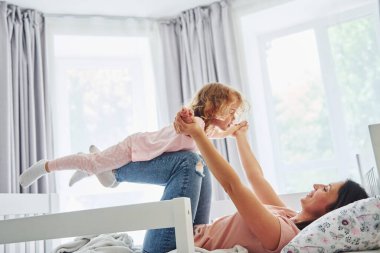 Hafta sonu vakti birbirinizle oynuyorsunuz. Genç bir anne ve küçük kızı evde birlikte günlük kıyafetler giyiyorlar..