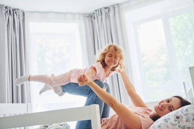 Hafta sonu vakti birbirinizle oynuyorsunuz. Genç bir anne ve küçük kızı evde birlikte günlük kıyafetler giyiyorlar..