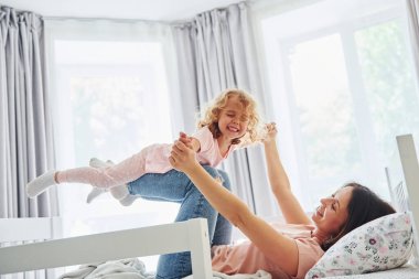 Hafta sonu vakti birbirinizle oynuyorsunuz. Genç bir anne ve küçük kızı evde birlikte günlük kıyafetler giyiyorlar..