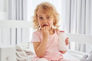 Kurabiye yiyerek kahvaltı yapmak. Gündüz vakti evde rahat giyimli şirin küçük bir kız var..